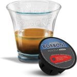 Caffè Borbone in capsule compatibili con Nespresso, Lavazza, Bialetti e Dolce Gusto disposte elegantemente accanto a una tazzina di espresso napoletano